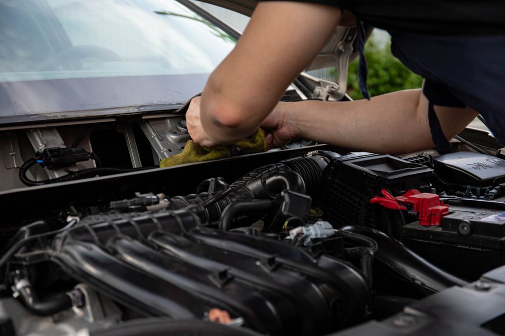 A detailer wiping down an engine bay with a microfiber cloth